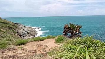 vue aérienne des vagues de l'océan frappant les falaises rocheuses dans l'océan bleu. vue de dessus des rochers côtiers dans l'océan de phuket. point de vue paysage du cap laem phromthep le matin. video