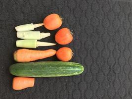 especias de cocina que tienen el nombre de fruta pero se utilizan como verduras, a saber, zanahorias, tomates, pepinos y maíz sobre un fondo oscuro foto