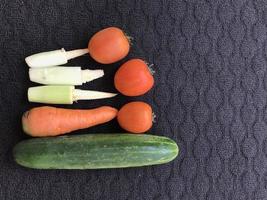 Kitchen spices that have the name Fruit but are used as vegetables, namely carrots, tomatoes, cucumbers and corn on a dark background photo