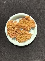 Floured fried chicken Photographed on a green plastic plate isolated on a dark background photo