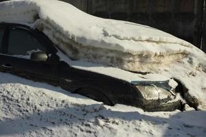 Car under snow. In winter in parking lot. Transport after snowfall. Machine under infusion of ice. photo