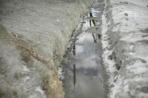 Path in water. Puddle on trail. Melting snow in city. photo