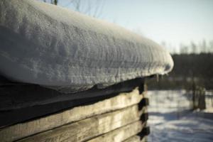 Winter in Russia. Snow on roof of hut. Old house made of wood. photo