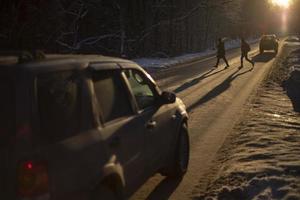 People are walking across street. Pedestrians break rules. Car is driving on highway. photo