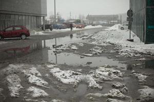 Muddy puddle of melted snow on road. Uncleaned parking. photo