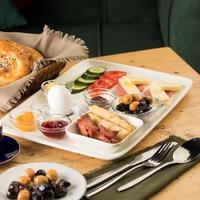 A breakfast plate and a basket of bread on a wooden table photo