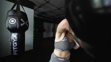 mujer en un gimnasio de boxeo golpea la bolsa con guantes de boxeo blancos video