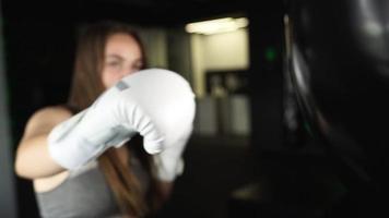 vrouw in een boksen Sportschool stoten zak met wit boksen handschoenen video