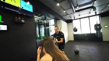 Frau im Fitnessstudio springt Kniebeugen mit Trainer video