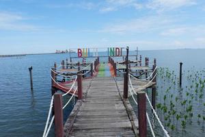 Pangkajene and Kepulauan, South Sulawesi, Indonesia - May 14, 2022, Wooden bridge road in mangrove area and clear blue skies photo