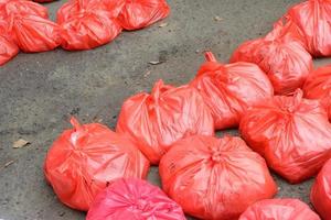 Red plastic bags containing meat neatly arranged on the asphalt photo