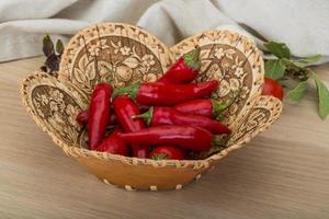 Chili peppers in a basket on wooden background photo