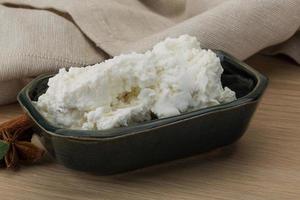 Ricotta cheese in a bowl on wooden background photo