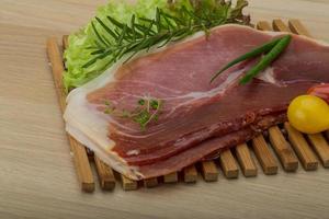 Prosciutto on wooden board and wooden background photo