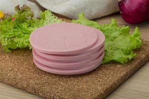 Ham sausage on wooden board and wooden background photo