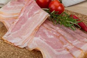 Bacon on wooden board and wooden background photo