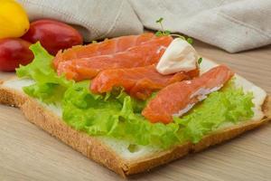 Salmon sandwich on wooden background photo