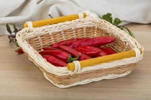 Chili peppers in a basket on wooden background photo