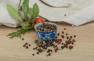 Pepper mix in a bowl on wooden background photo