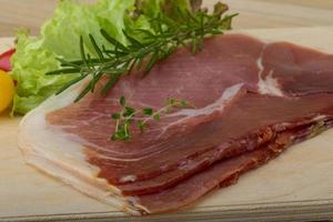 Prosciutto on wooden board and wooden background photo