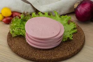 Ham sausage on wooden board and wooden background photo