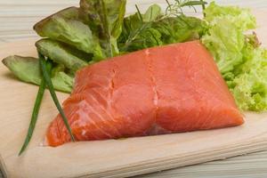 Salmon fillet on wooden board and wooden background photo