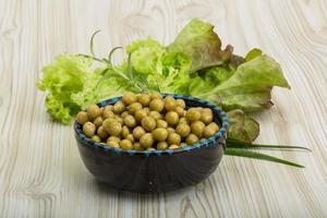 Marinated peas in a bowl on wooden background photo