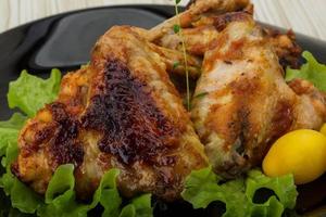 Chicken wings on the plate and wooden background photo