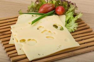 Maasdam cheese on wooden board and wooden background photo