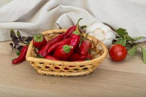 chiles en una canasta sobre fondo de madera foto