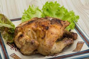 Roasted chicken on the plate and wooden background photo