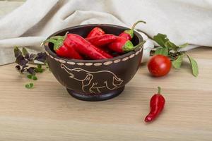 Chili peppers in a bowl on wooden background photo