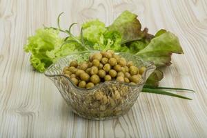 Marinated peas in a bowl on wooden background photo