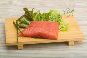 Salmon fillet on wooden board and wooden background photo