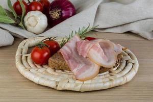 Bacon sandwich on wooden board and wooden background photo