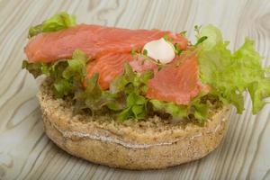 Salmon sandwich with thyme on wooden background photo