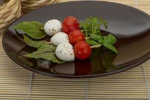 Caprese salad on the plate and wooden background photo