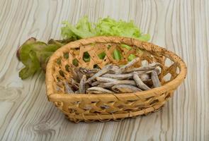 Dries anchovy in a basket on wooden background photo