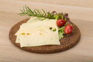 Maasdam cheese on wooden board and wooden background photo