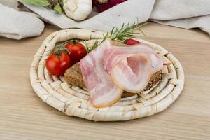 Bacon sandwich on wooden board and wooden background photo