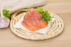 Sliced salmon on wooden board and wooden background photo