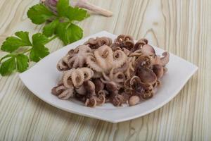 Boiled octopus on the plate and wooden background photo