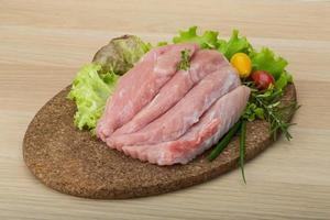 Raw pork schnitzel on wooden board and wooden background photo