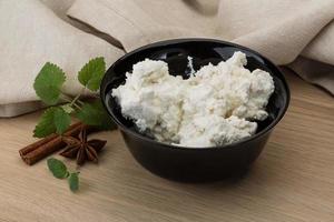 Ricotta cheese in a bowl on wooden background photo