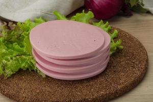 Ham sausage on wooden board and wooden background photo