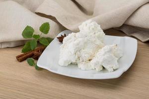 Ricotta cheese on the plate and wooden background photo