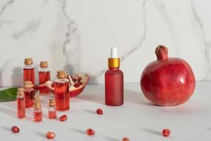 Red dropper bottles of pomegranate serum or oil for face and body standing on a white background photo