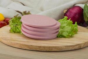 Ham sausage on wooden board and wooden background photo