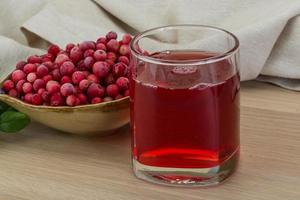 jugo de arándano rojo en un recipiente sobre fondo de madera foto