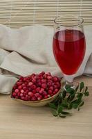 Cowberry juice in a bowl on wooden background photo